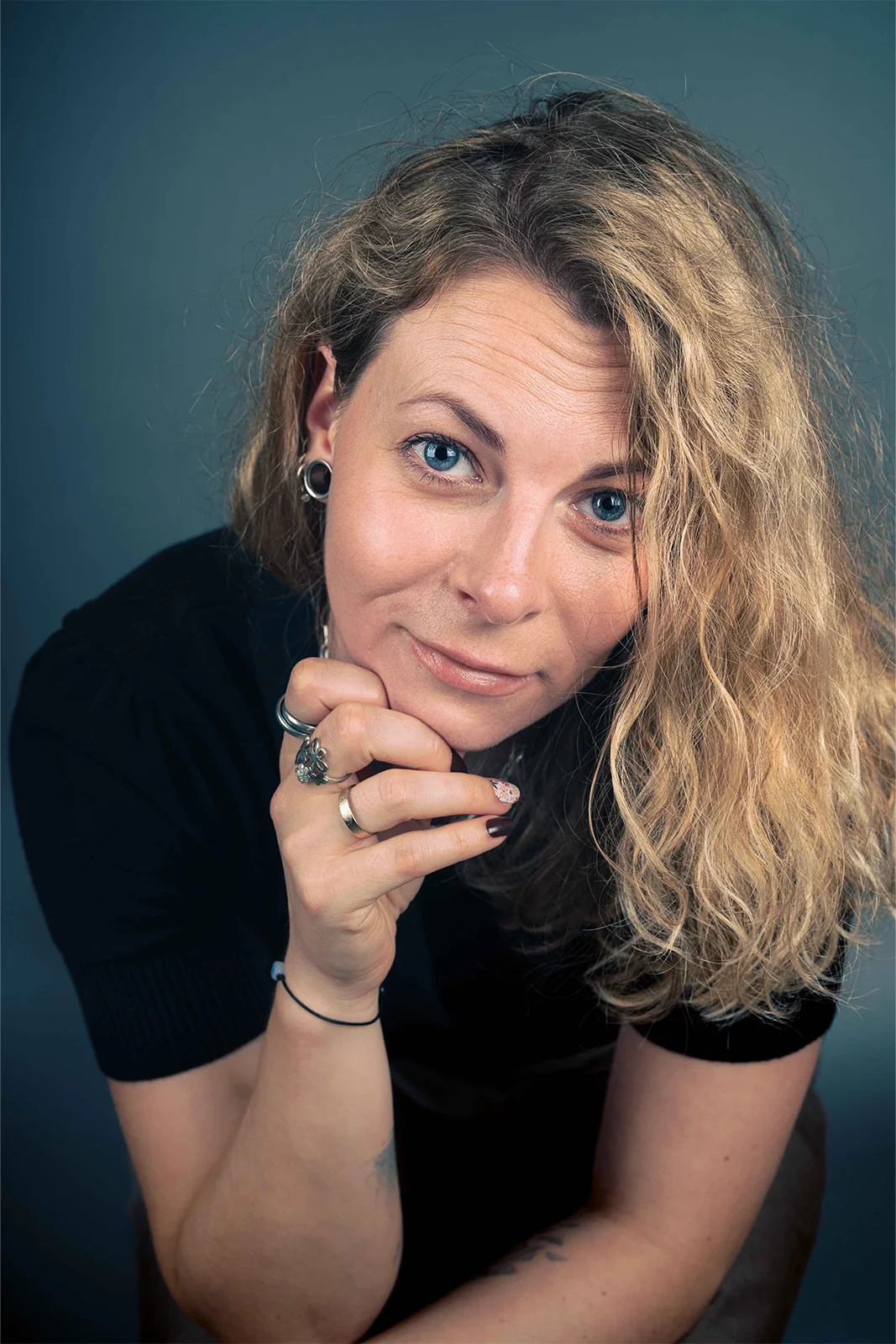 Portrait d'une femme souriante, accoudée devant un fond sombre dans un studio à Nancy